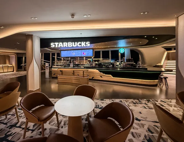 Starbucks on Norwegian Aqua with nearby cafรฉ seating and modern atrium design.