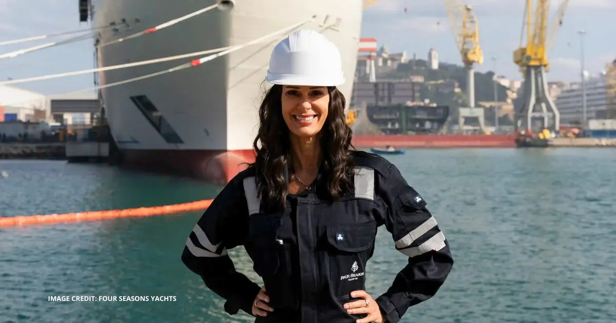 Captain Kate McCue wearing a hard hat in front of Four Seasons I during construction for Four Seasons Yachts.