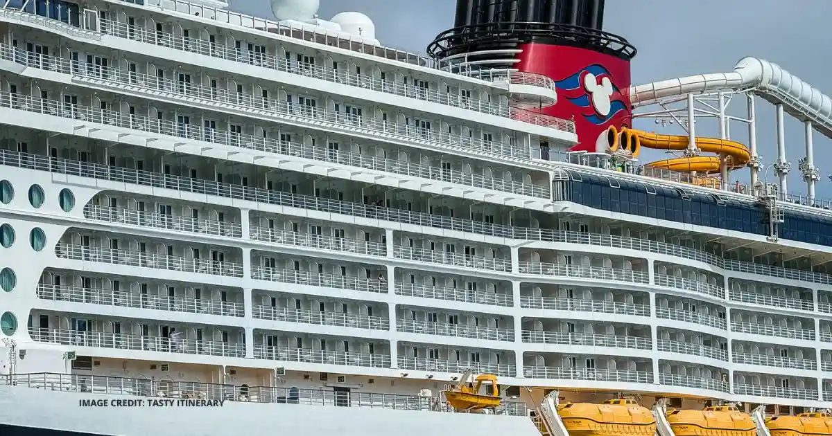 Disney Cruise Line ship exterior with Mickey Mouse funnel, balcony staterooms, and yellow lifeboats.