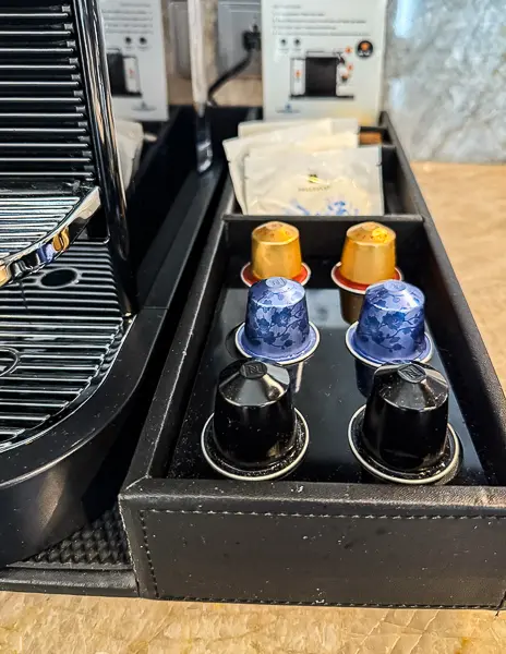 Close-up of stocked Nespresso capsules and tea supplies beside the coffee machine in an NCL Haven suite.