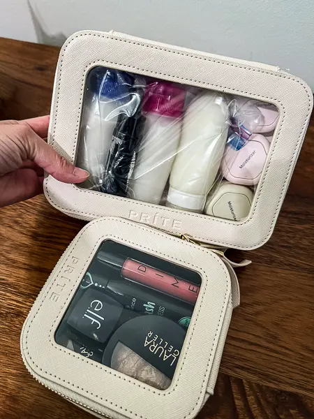Two travel bags on a table, with the larger bag filled with toiletries and the smaller bag holding makeup and beauty products.