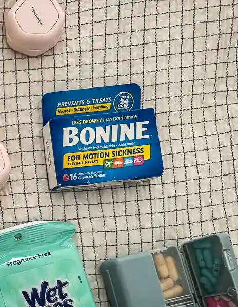 Bonine motion sickness medication beside travel toiletries, sanitizing wipes, and a pill organizer.