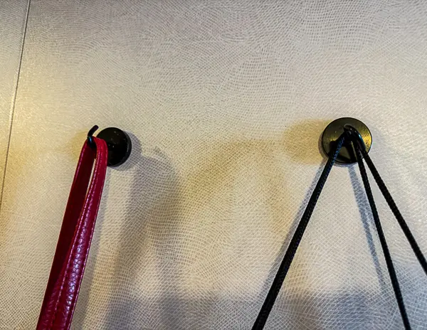 Magnetic hooks attached to a cruise cabin wall holding a bag and straps.
