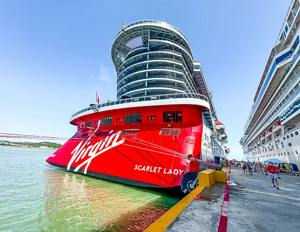 Virgin Voyages Scarlet Lady secured to a cruise pier with thick mooring lines.