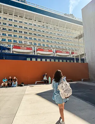 Kathy looking up at a large cruise ship docked at the terminal.