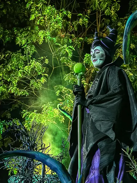 Maleficent holding her staff amid green lighting and fog at Oogie Boogie Bash in Disney California Adventure.