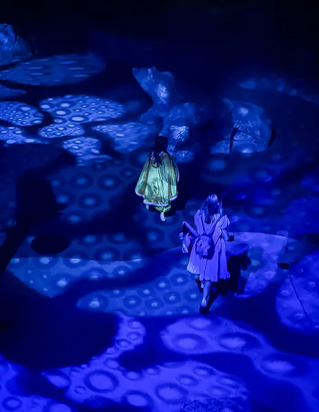 Guests walking through blue lighting effects inside Villains Grove at Oogie Boogie Bash in Disney California Adventure.